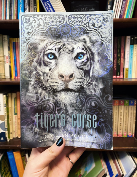 Hand holding book in front of bookshelf