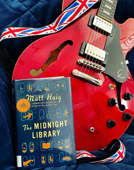 Book in front of red electric guitar