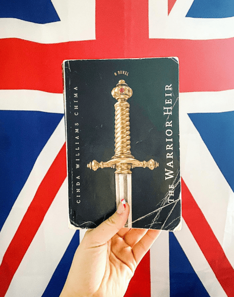 Hand holding book in front of British flag