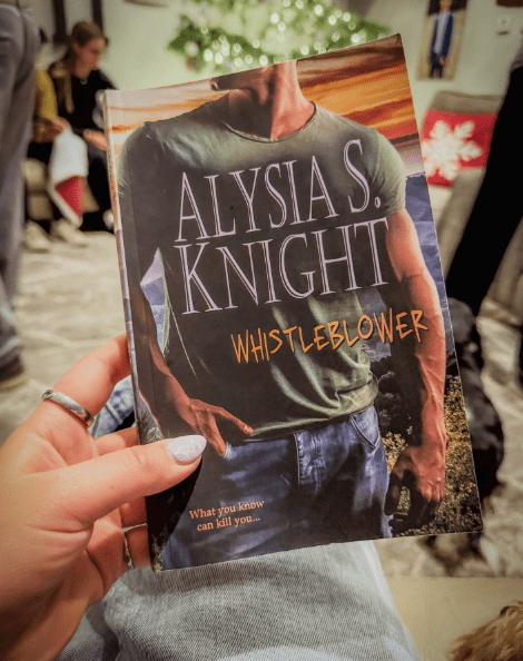 Hand holding book in front of Christmas tree
